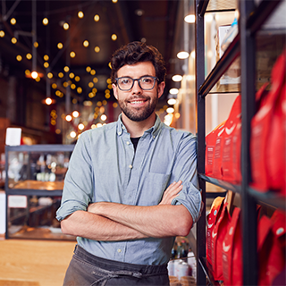 Business owner standing near a display of coffee bags in a cafe