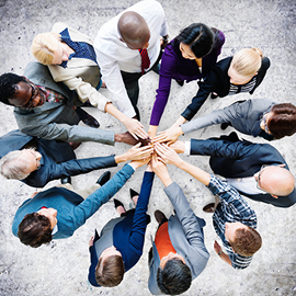 Group of people in a huddle with their hands meeting in the center