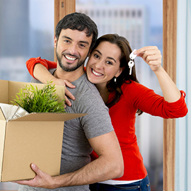 Young couple holding packing boxes and keys to their new home