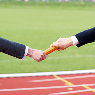 two people in suits handing off a relay race baton