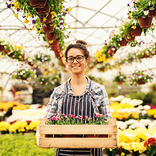young woman with box of flowers inside a greenhouse