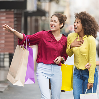two young girls with shopping bags looking excited