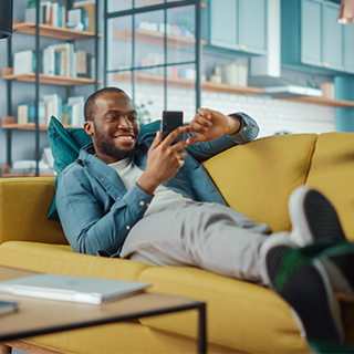 African American male lounging on couch with cellphone