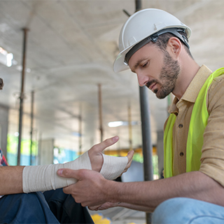 worker helping wrap a bandage around a coworker's arm