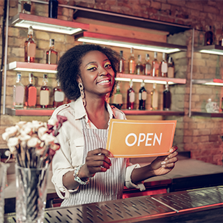 Female African American business owner holding an OPEN sign 