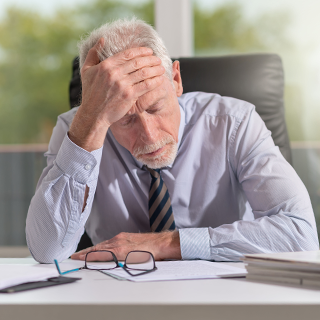 mature businessman with hand on head looking worried
